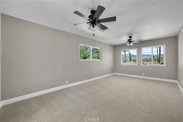 spare room with baseboards, ceiling fan, visible vents, and light colored carpet