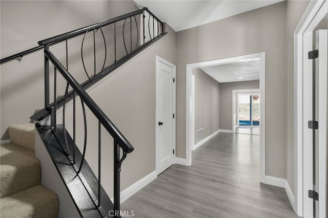 staircase with baseboards, wood finished floors, and visible vents