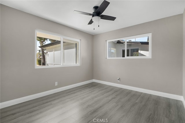 empty room with baseboards, plenty of natural light, and wood finished floors