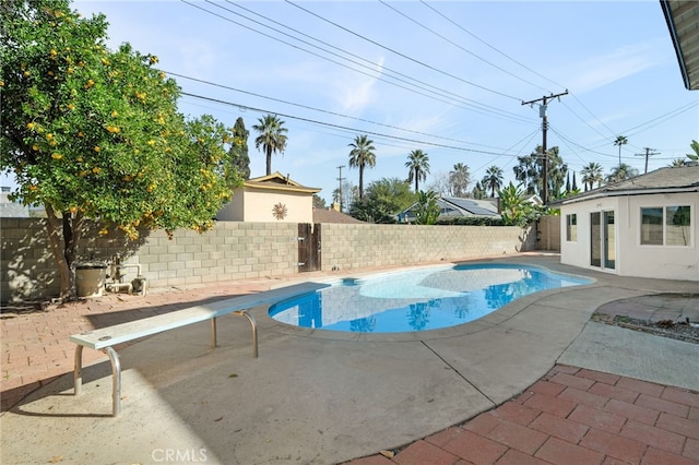 view of pool featuring a diving board, a fenced in pool, a fenced backyard, and a patio area