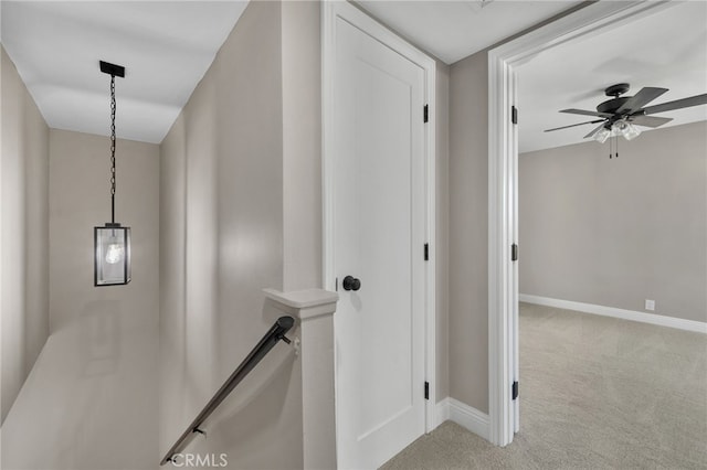 hall featuring baseboards, light colored carpet, and an upstairs landing