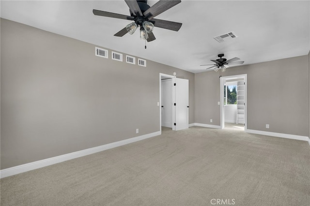 empty room with visible vents, a ceiling fan, and light colored carpet