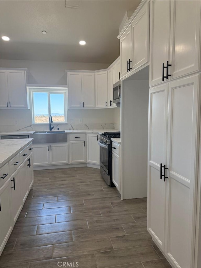 6472 Cayucos Dr, Phelan, CA 92371 - kitchen featuring appliances with stainless steel finishes, a sink, white cabinets, recessed lighting, and wood finish floors
