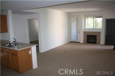 unfurnished living room featuring a sink, a fireplace, and carpet flooring