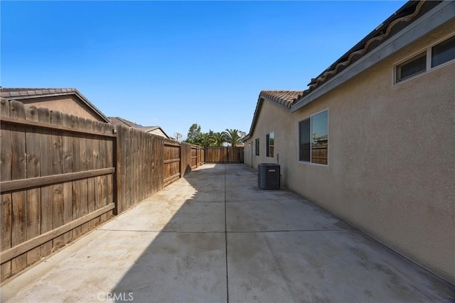 view of home's exterior with a tiled roof, central AC, a fenced backyard, a patio, and stucco siding