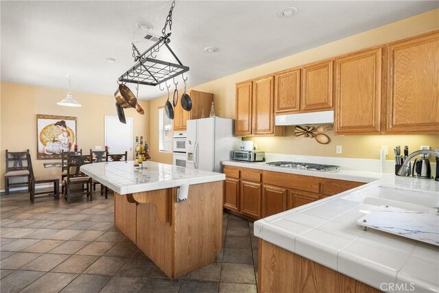 833 W Orange Heights Ln, Corona, CA 92882 - kitchen with white appliances, tile counters, under cabinet range hood, a center island, and a sink