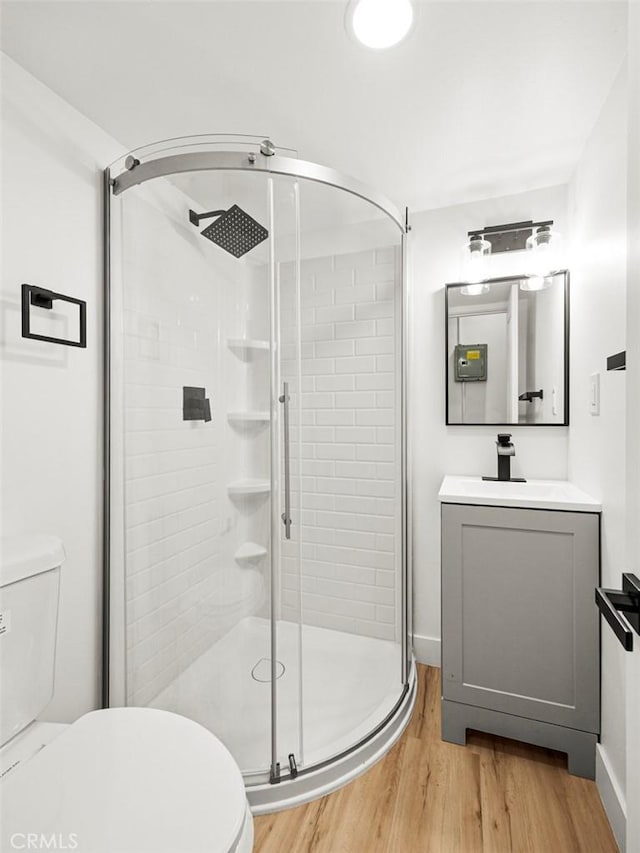 bathroom featuring toilet, wood finished floors, and a stall shower