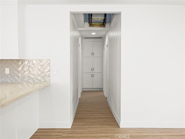 corridor with baseboards and light wood finished floors