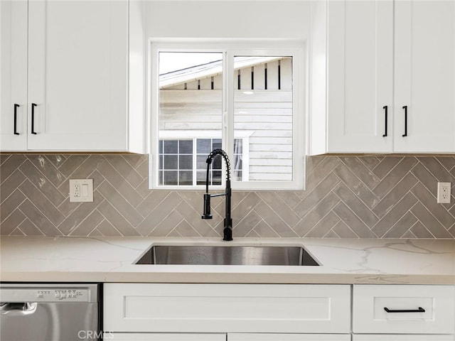 kitchen with white cabinets, light stone counters, a sink, tasteful backsplash, and stainless steel dishwasher