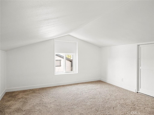 additional living space featuring carpet floors, baseboards, and vaulted ceiling