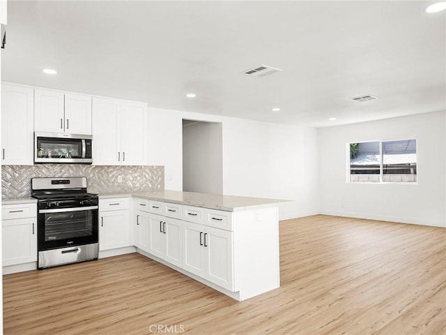 kitchen featuring visible vents, appliances with stainless steel finishes, tasteful backsplash, a peninsula, and light wood-style floors