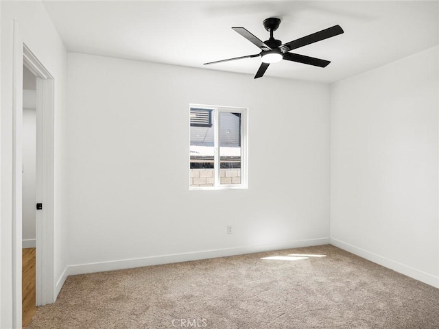 empty room with baseboards, a ceiling fan, and light colored carpet