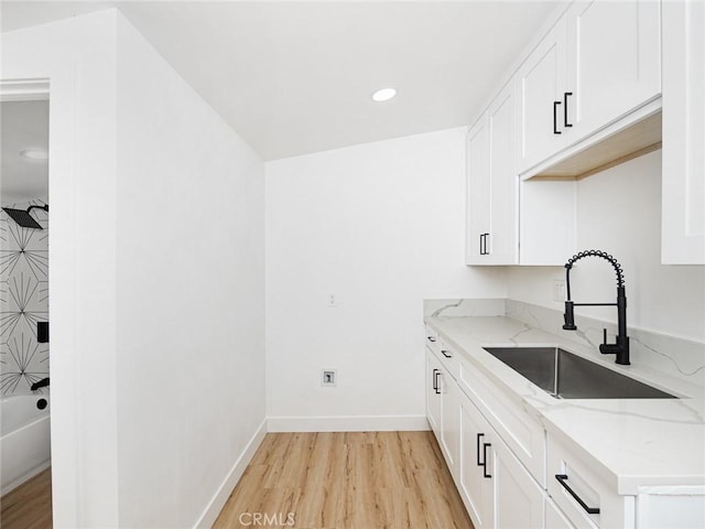 kitchen with white cabinets, light stone counters, a sink, light wood-style flooring, and recessed lighting