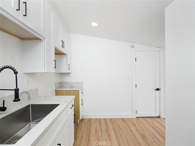 kitchen featuring white cabinetry, a sink, and light wood-style flooring