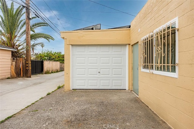 garage featuring fence and driveway