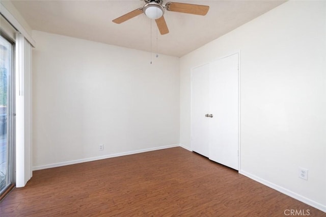 spare room with baseboards, a ceiling fan, plenty of natural light, and wood finished floors