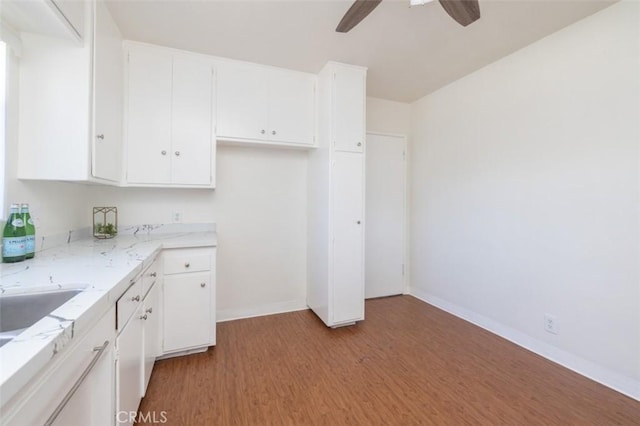 kitchen featuring a ceiling fan, baseboards, light wood-style flooring, and white cabinets