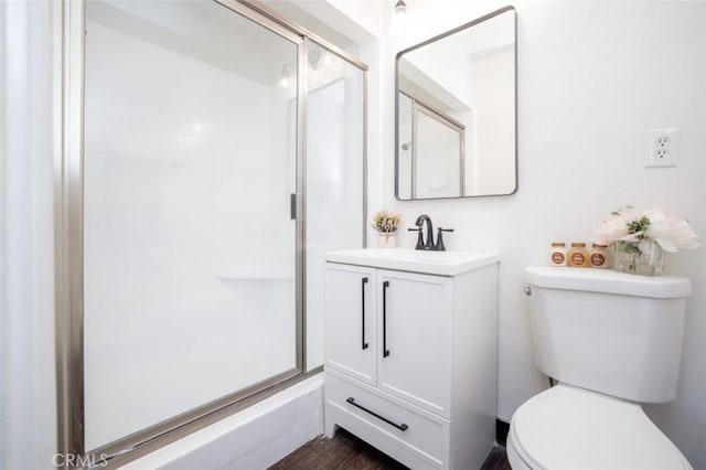 bathroom with vanity, toilet, a shower stall, and wood finished floors