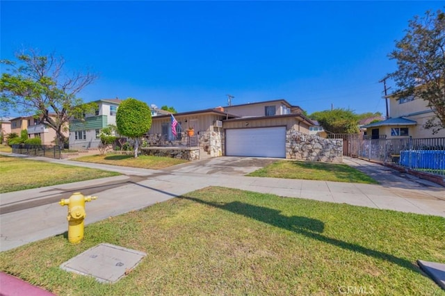 view of front of property featuring fence, concrete driveway, stone siding, and a front yard