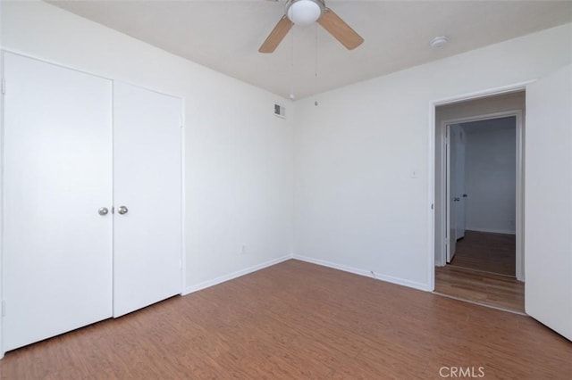 unfurnished bedroom featuring a closet, baseboards, visible vents, and wood finished floors