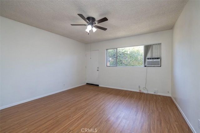 unfurnished room with wood finished floors, a ceiling fan, cooling unit, a textured ceiling, and baseboards
