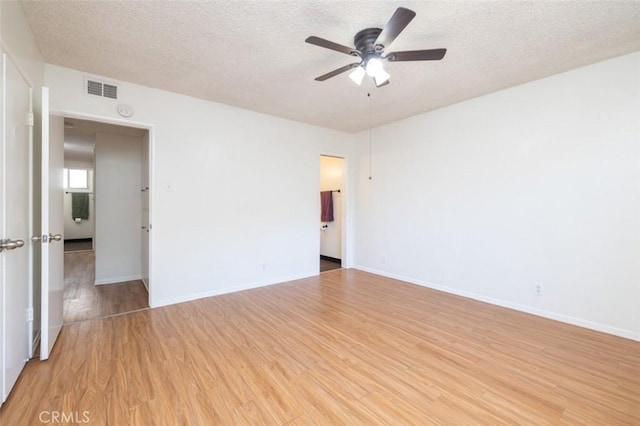empty room with a textured ceiling, visible vents, ceiling fan, baseboards, and light wood-style floors