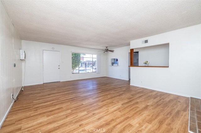 unfurnished living room with light wood-style flooring, a textured ceiling, visible vents, baseboards, and ceiling fan