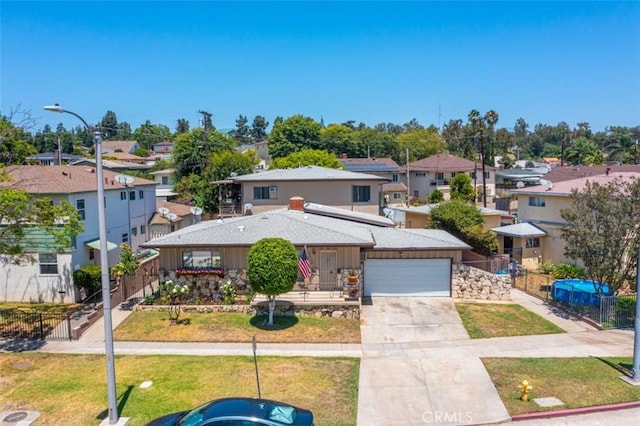 traditional home featuring an attached garage, a residential view, fence, concrete driveway, and a front yard