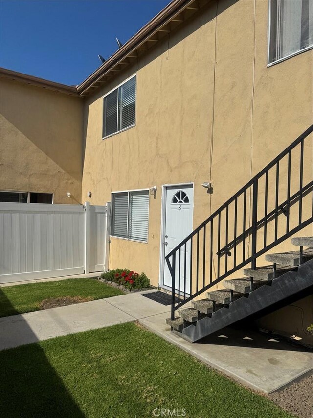 4302 Howard Ave Unit 5, Los Alamitos, CA 90720 - property entrance featuring a lawn, fence, and stucco siding