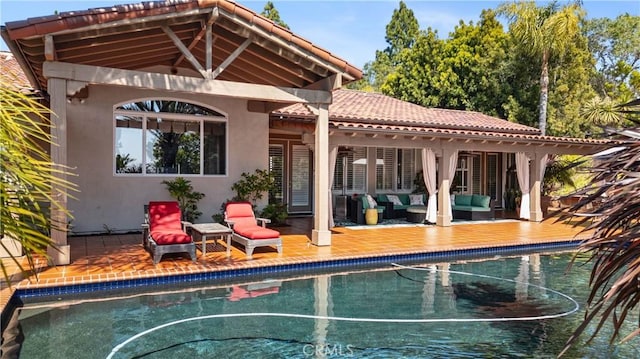 rear view of house with stucco siding, an outdoor living space, a patio area, and an outdoor pool