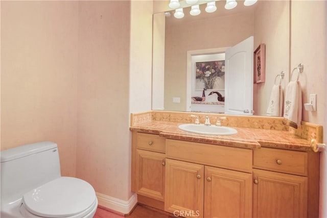 bathroom featuring toilet, baseboards, and vanity
