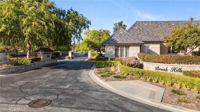 view of road with a gated entry and curbs