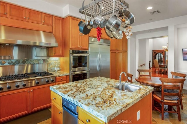 kitchen featuring visible vents, range hood, tasteful backsplash, a sink, and appliances with stainless steel finishes
