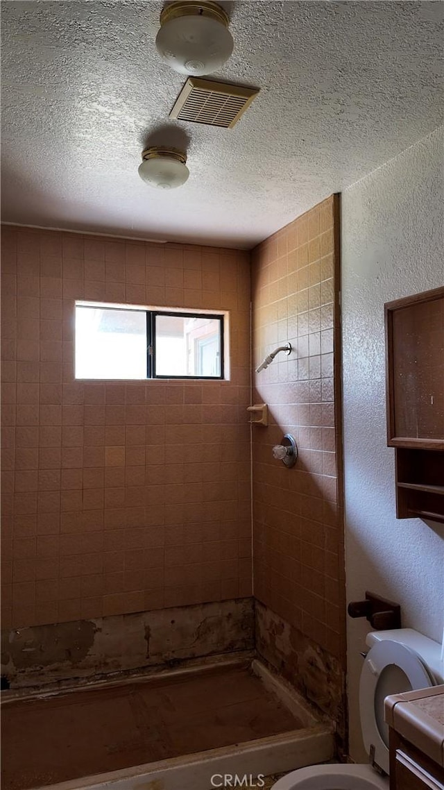 full bathroom featuring a textured wall, toilet, a textured ceiling, a shower stall, and visible vents
