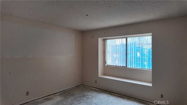unfurnished room with baseboards and a textured ceiling