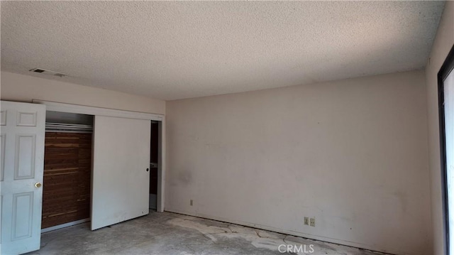 unfurnished bedroom with a closet, concrete floors, a textured ceiling, and visible vents