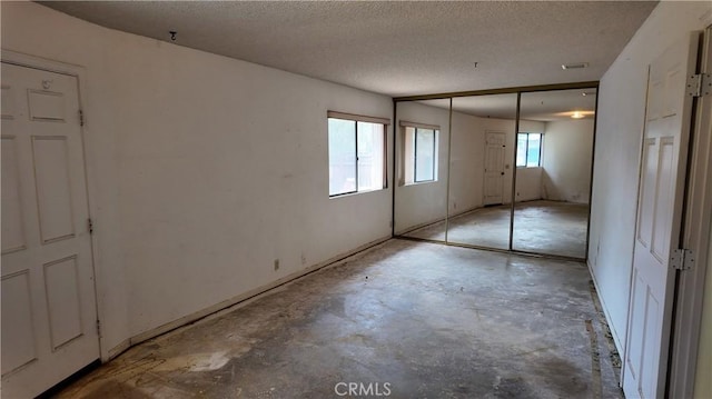 unfurnished bedroom featuring a closet, a textured ceiling, and unfinished concrete floors