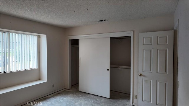 unfurnished bedroom featuring a textured ceiling, visible vents, and a closet