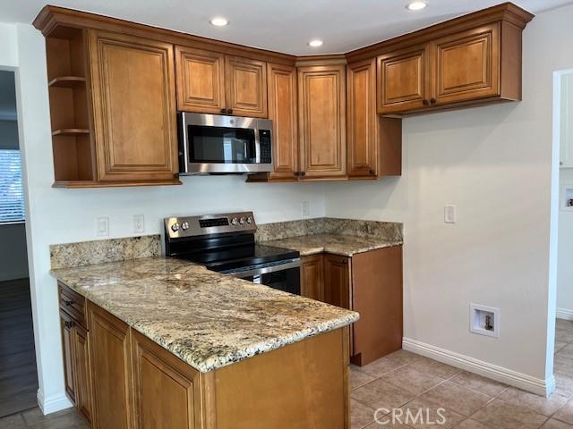 14675 Red Hill Ave, Tustin, CA 92780 - kitchen with brown cabinetry, baseboards, light stone countertops, and stainless steel appliances