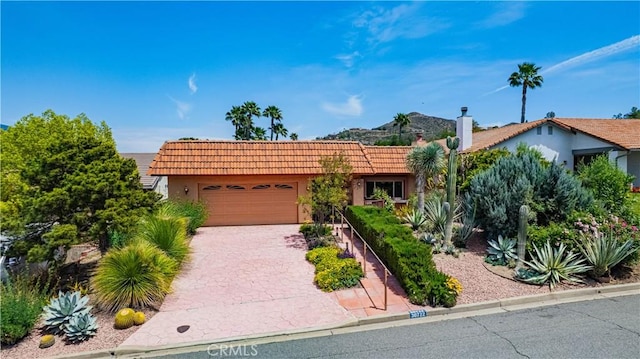 view of front of property featuring a garage, stucco siding, a tiled roof, and driveway