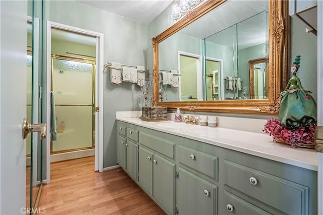 full bathroom with a stall shower, wood finished floors, and vanity