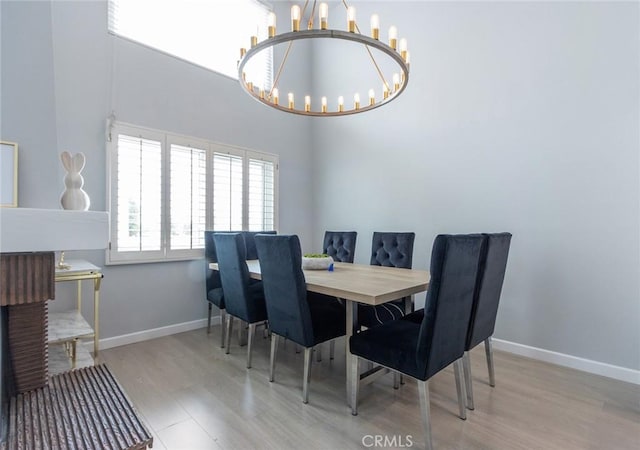 dining room with baseboards, a high ceiling, wood finished floors, and a chandelier
