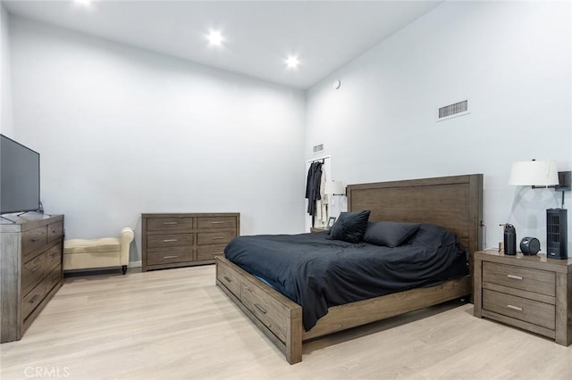 bedroom with visible vents, recessed lighting, light wood-style flooring, and a towering ceiling