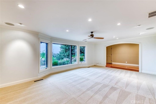 spare room with crown molding, baseboards, light colored carpet, and visible vents
