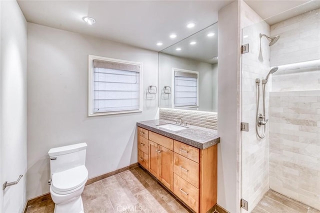 full bathroom with vanity, toilet, baseboards, tiled shower, and recessed lighting