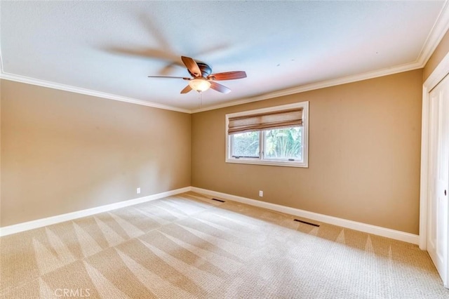 empty room with baseboards, ornamental molding, a ceiling fan, and light colored carpet