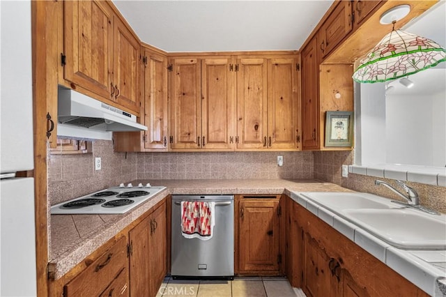 kitchen featuring brown cabinetry, tasteful backsplash, a sink, under cabinet range hood, and white appliances
