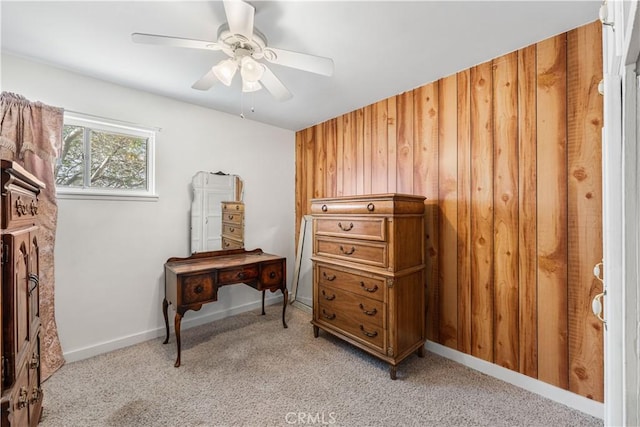 misc room with wooden walls, ceiling fan, light carpet, and baseboards