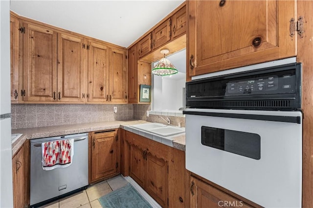 kitchen featuring stainless steel dishwasher, oven, a sink, and tasteful backsplash