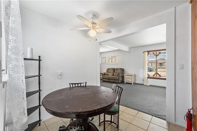 dining space with baseboards, a ceiling fan, light tile patterned flooring, and light carpet